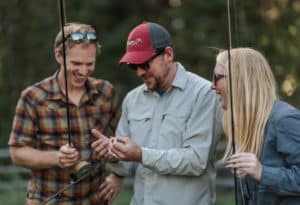 Man helping two fishers get their lines set up with bait and hooks