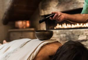 Woman getting massage with singing bowl on her back at Mountain Sky Guest Ranch