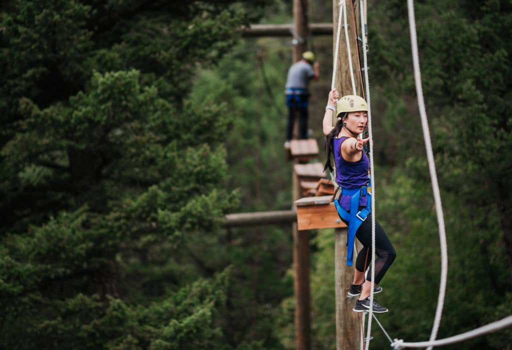 Woman climbing across ropes course at Mountain Sky Guest Ranch