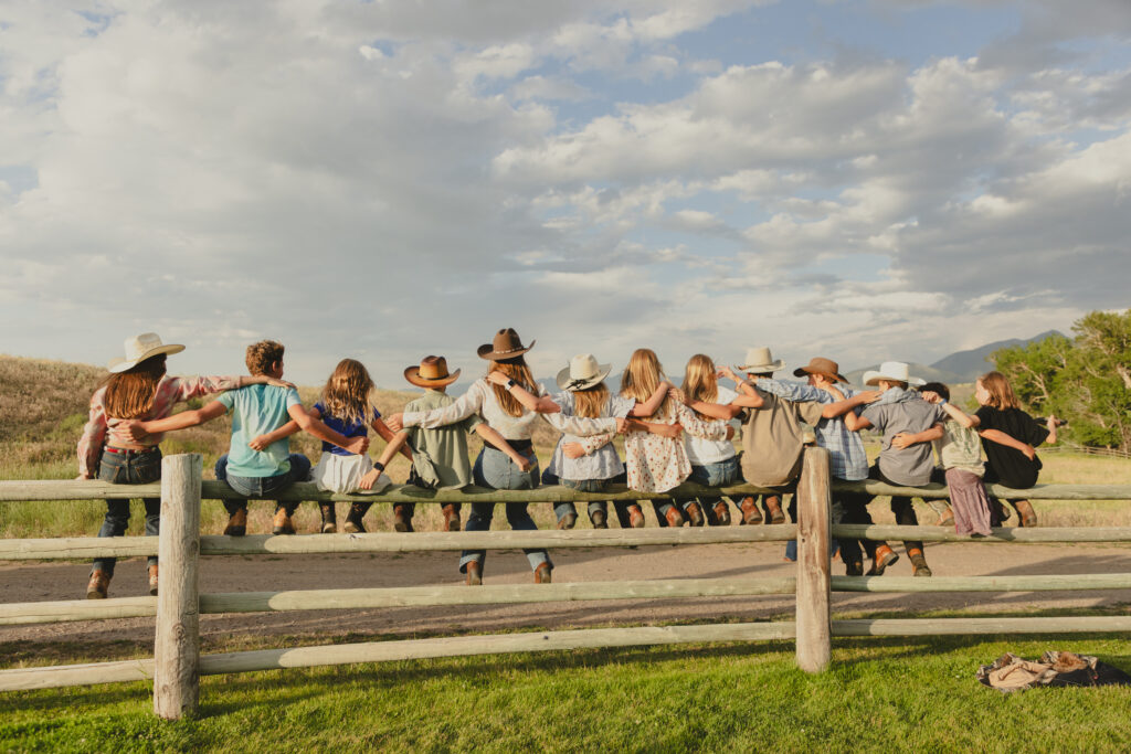 Guests at Mountain Sky Ranch in Montana sit on a Fence. Guests love the nature and atmosphere of Montana's working dude ranch.